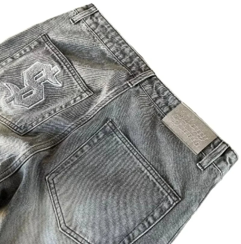 Close-up of gray denim jeans with brand logo and label on a white background
