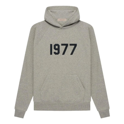 Gray essentials hoodie with '1977' printed on the front against a white background