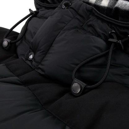 Close-up of a black quilted jacket with buttons and drawstrings on a white background