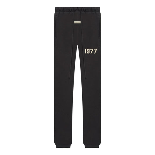 Black essentials sweatpants with '1977' printed on the front against a white background