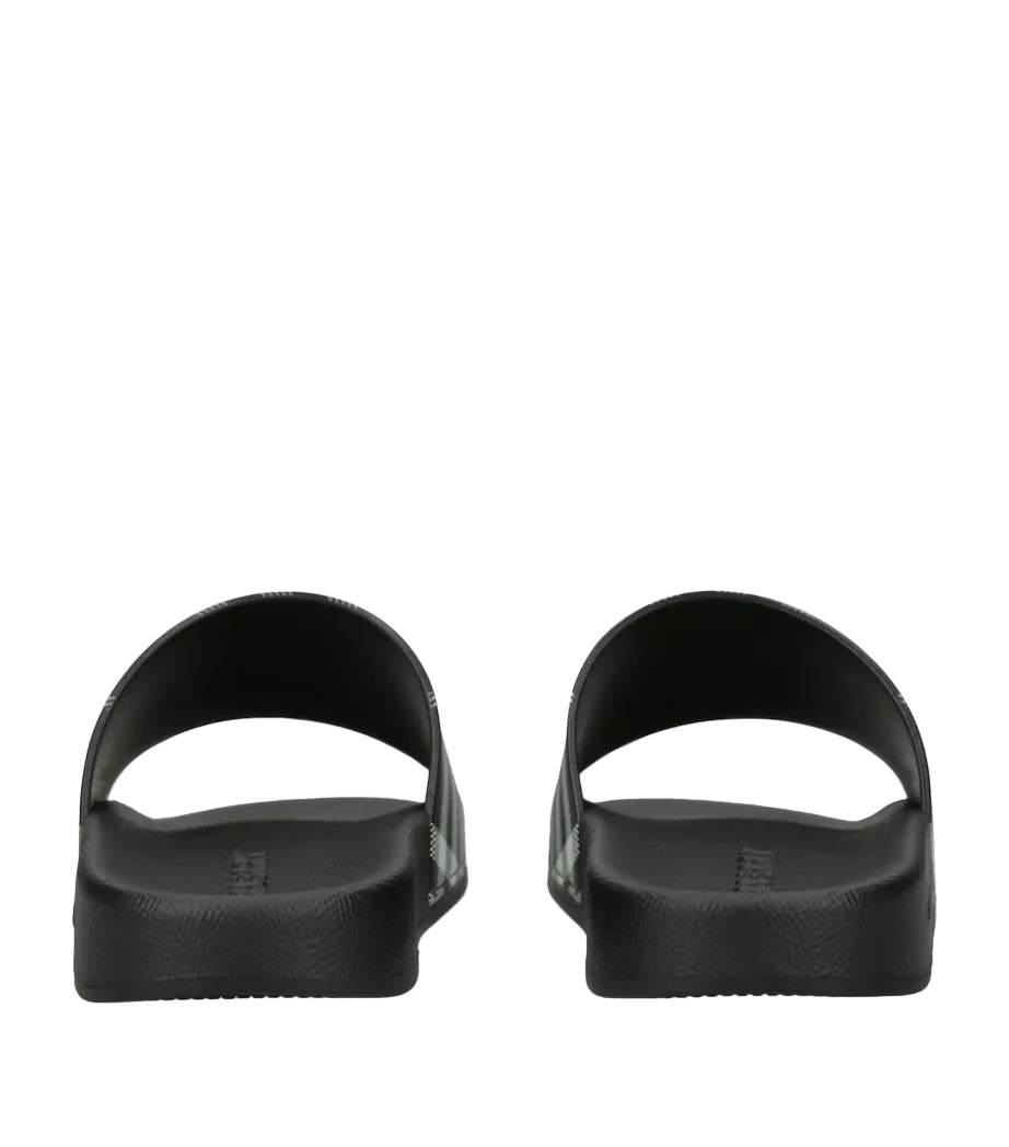 A pair of Burberry checkered slide sandals shown from the back, featuring thick black textured soles and, set against a plain white background.