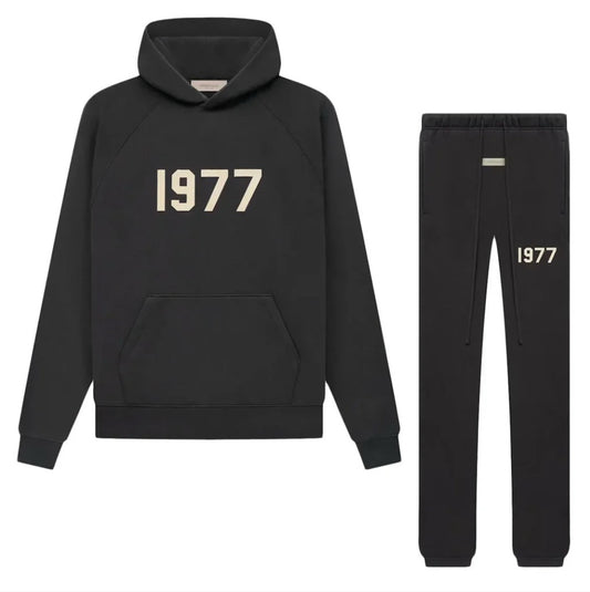 Black essentials fear of god hoodie and pants set with '1977' print on a white background